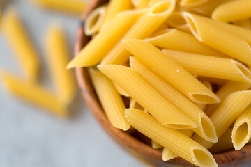 Flat lay of bowl with raw penne pasta on ultimate gray