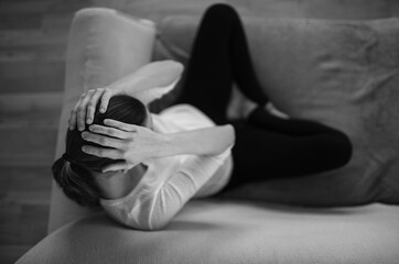 Young woman sitting on a couch feeling sad and tired 