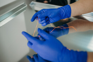 orange dental floss in the hands of a doctor