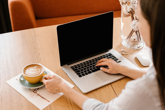 Young woman drinking coffee while working with laptop