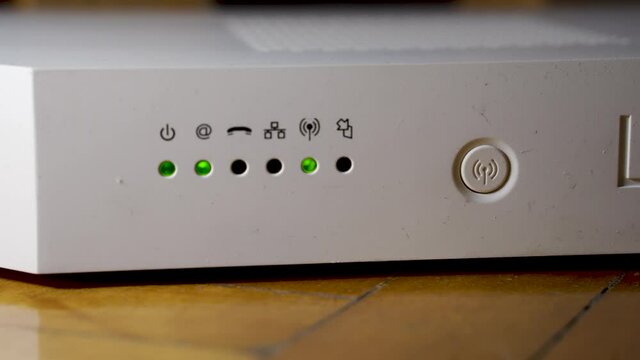 Close up of a Modern white wireless internet wifi router/modem with flashing led lights with network related icons and a power button