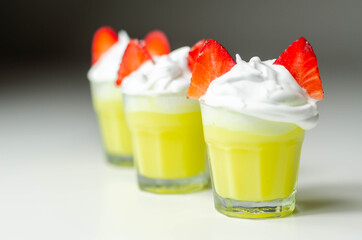 Egg liqueur in shot glass decorated with fluffy whipped cream and pieces of strawberry in the shape of bunny ears