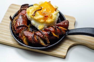 Grilled sausage with onion and egg in a cloud, all served on a cast iron pan
