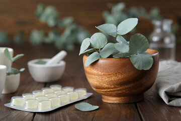 Wooden mortar of green eucalyptus leaves and lozengers for care sore throat and cough.