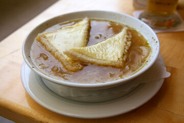 Traditional French onion soup. Croutons with cheese in broth. On a table in a cafe
