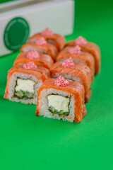 Sushi with salmon and cream cheese on a green background. Close-up