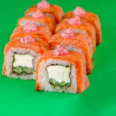 Sushi with salmon and cream cheese on a green background. Close-up