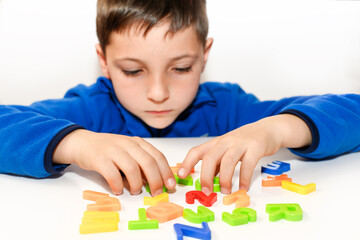 Child playing with colored letters on white background.