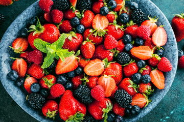 Berries colorful assorted mix of strawberry, blueberry, raspberry, blackberry on dark background