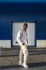 Chico negro apuesto posando delante de una pared azul y puerta blanca