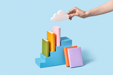 Papercraft cloud in a hand above shelf of books.