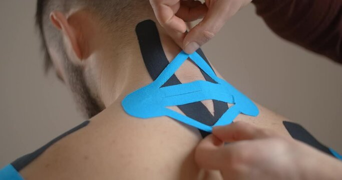 Kinesiologist sticks tapes to the neck of patient, recovery of an athlete after injury, kinesiotapes in the therapy of osteochondrosis, , 4k 60p Prores HQ 10 bit