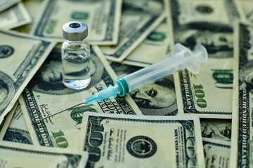 Vaccine vial and syringe on the background of one hundred dollar bills