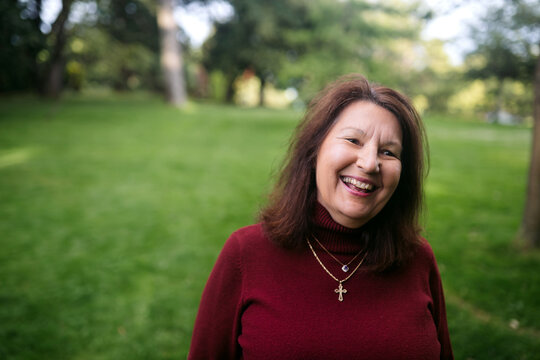Portrait of older warm, happy woman outside in nature.