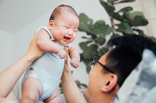 Asian father lifting baby son