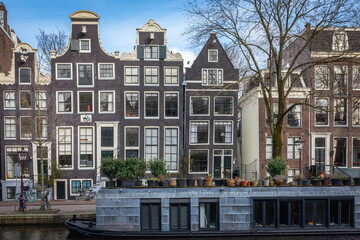 Fototapeta premium A view of the houseboat and a typical dutch houses along the Prinsengracht canal in Amsterdam