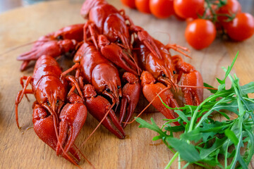 Boiled red crayfish lie on a wooden table, fresh herbs and tomatoes.Concept:beer appetizer, delicacy, crayfish meat.