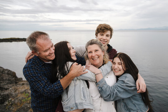 Happy family with teenagers outside near ocean.