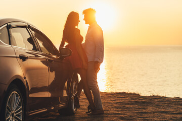 The beautiful couple standing near the car on the sea shore
