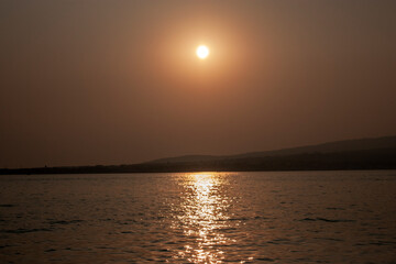 Sunset over the sea against the backdrop of the coast. Evening of the day at sea in clear weather....