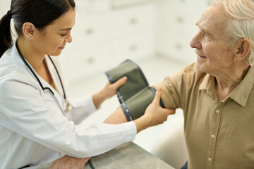 Professional medic preparing to measure blood pressure of senior gentleman