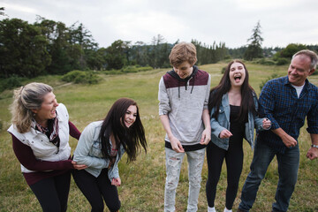 Laughing parents and teenagers together in field