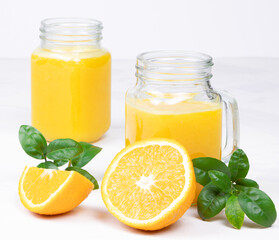 Fototapeta na wymiar Orange juice and green leaves on a white background.A glass of orange juice and orange fruit. Healthy food. Vegan food. Diet and proper nutrition.