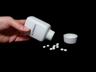 Human hand spill ivermectin pills on black table, covid 19 treatment