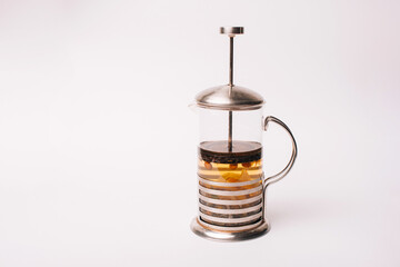 Photo of a French press tea pot half full of tea over white background.