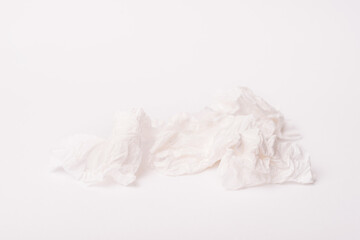Photo of a crumpled white used paper napkin over white background.