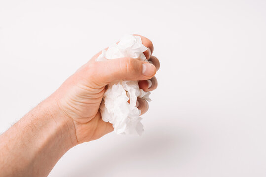 A Male Hand Is Holding A Bunch Of  White Used Napkins Over White Background.