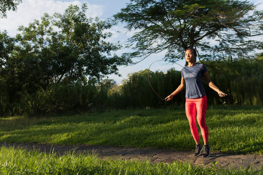 A woman in a park is doing jumping ropes.