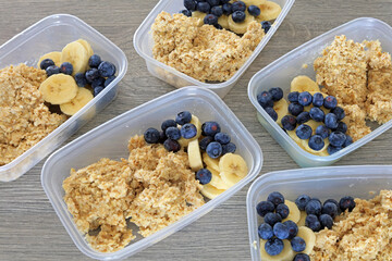 Blueberries And Sliced Bananas In Plastic Food Storage Containers With Porridge Oats. Balanced Breakfast