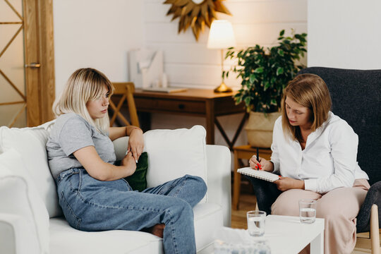 Psychologist writing down complaints of sad client