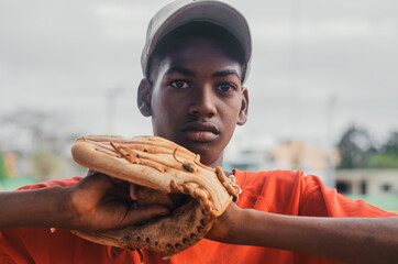 boy with brown skin and latin origin playing baseball in the park with ball, glove and bat, dark...