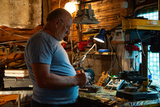 Senior craftsman soldering microcircuit in workshop