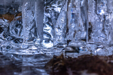 Icicles and a drop of melt water close-up. Snow melting. The beginning of the warm season, the end of winter. Bright illustration. Rustic sunset in early spring. Macro