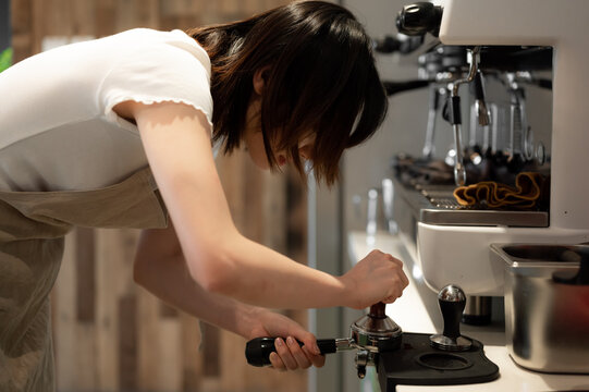 Young female worker making coffee