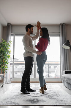 Man dancing with ethnic girlfriend at home
