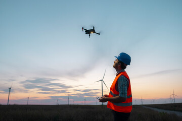 Drone operated by construction worker inspecting wind turbine