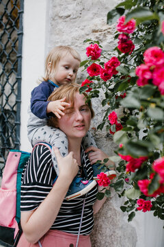 Mother and son sitting on her shoulders near of the roses