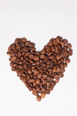 Freshly roasted coffee beans in shape of a heart isolated on white background. top view