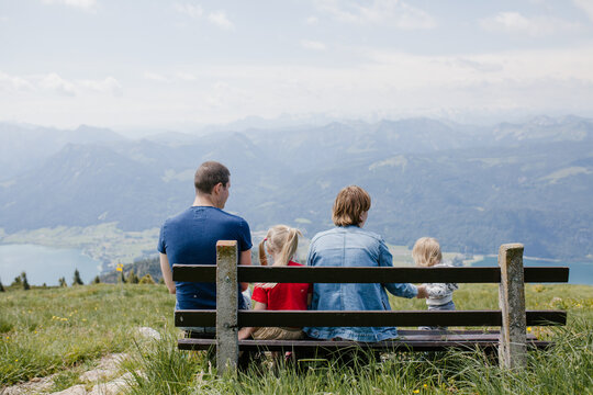 Family sitting on the bench outside together looking at the mountains