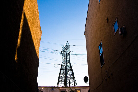 Electrical Tower And Power Lines As Seen Between Two Buildings In A City