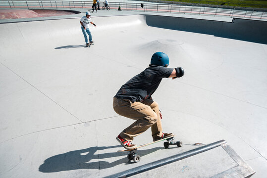 Front view of mid aged man skateboarder in his forties performing stunt on ramp at skate park with safety helmet - Powered by Adobe