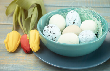 Obraz na płótnie Canvas easter eggs in basket, plates, cutlery and flowers