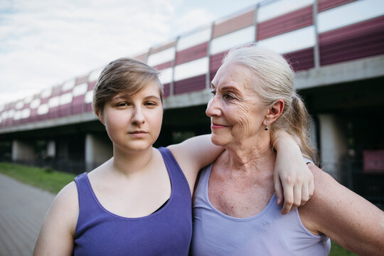Senior woman and teenage girl relax in the park after a run.