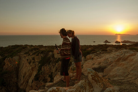 Young Couple at sunset on top of a cliff.