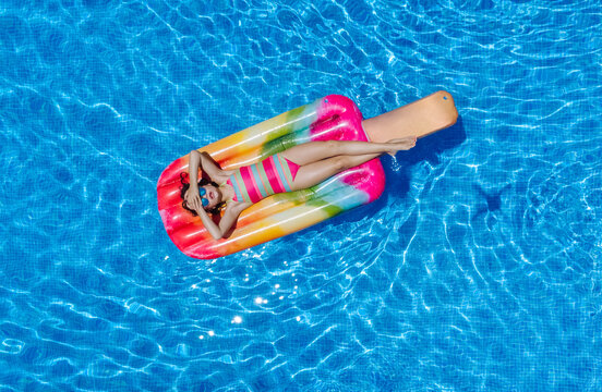 Little kid floating on inflatable mattresses in pool