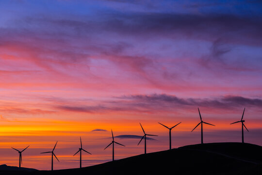 wind turbines in purple and orange setting sun